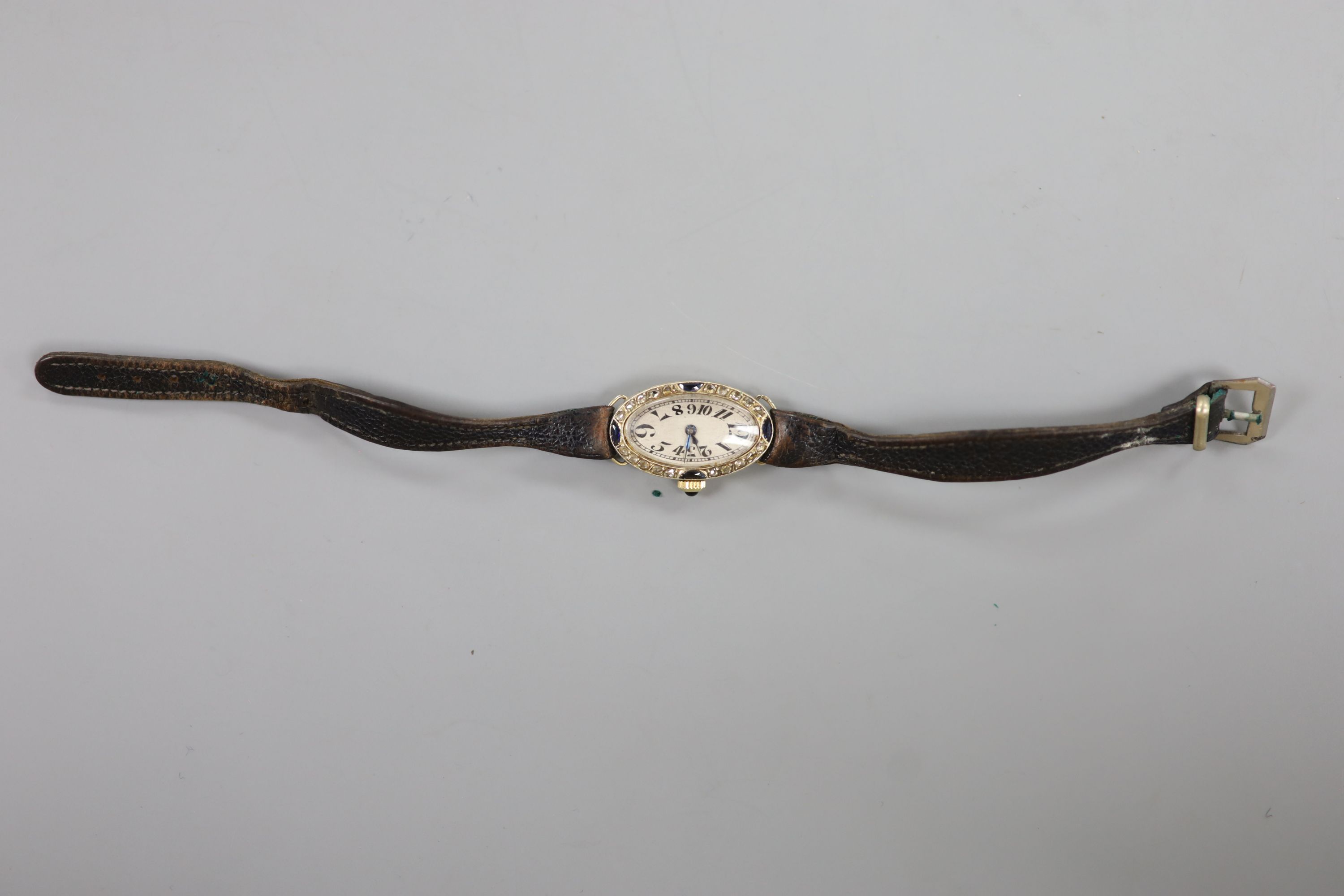 A lady's 1930's/1940's French yellow metal (18ct poincon mark), rose cut diamond and synthetic? sapphire set oval cocktail watch, with tumbling numerals, on a leather strap.